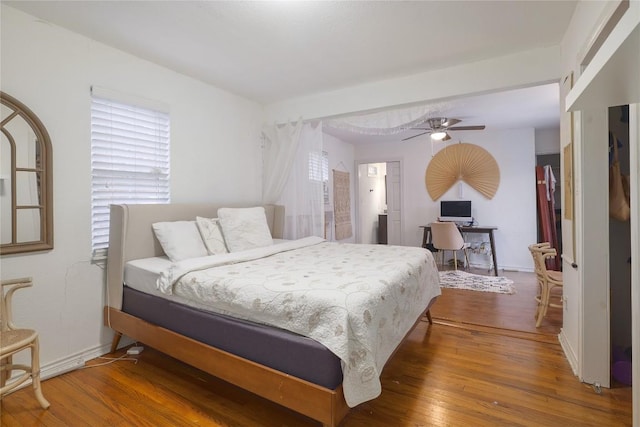 1406 Webberville Rd, Austin, TX 78721 - bedroom with hardwood / wood-style flooring, multiple windows, an office area, and a ceiling fan