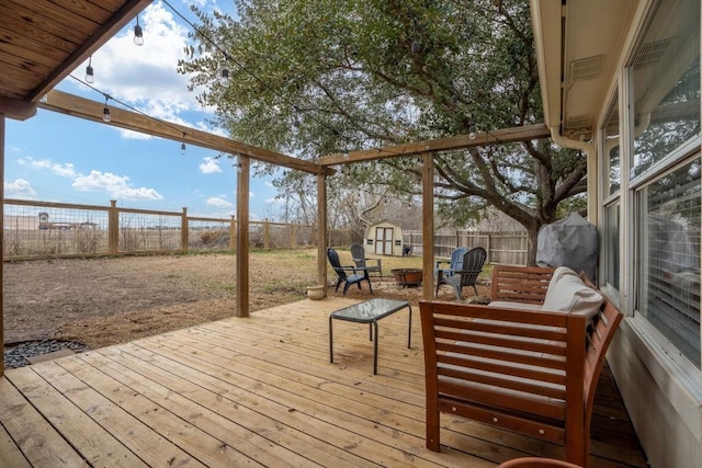 wooden terrace featuring an outdoor living space with a fire pit and a storage shed