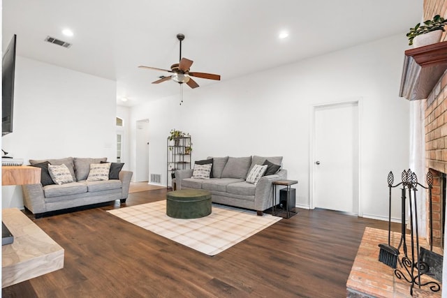 living room featuring ceiling fan, a fireplace, and dark hardwood / wood-style flooring