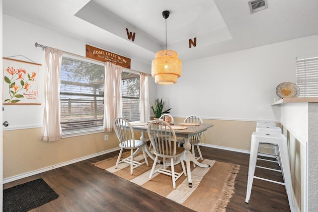 dining space featuring a tray ceiling and dark hardwood / wood-style floors