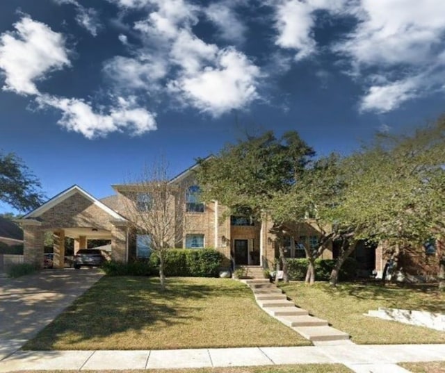 view of front of home featuring brick siding, driveway, and a front lawn