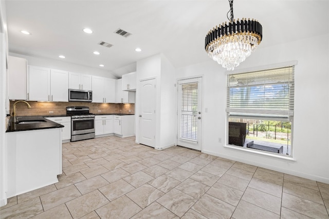 kitchen featuring sink, appliances with stainless steel finishes, white cabinetry, backsplash, and decorative light fixtures