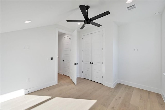 unfurnished bedroom with vaulted ceiling, ceiling fan, light wood-type flooring, and a closet