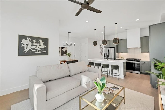 living room featuring ceiling fan with notable chandelier and light hardwood / wood-style flooring