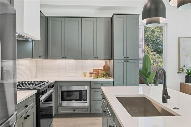 kitchen featuring gas stove, sink, stainless steel microwave, and backsplash