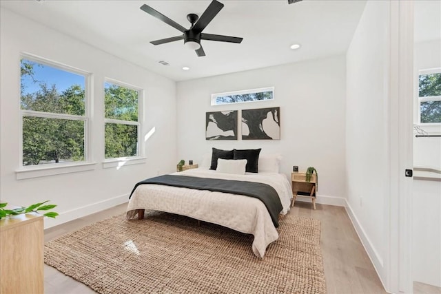 bedroom with multiple windows, ceiling fan, and light wood-type flooring