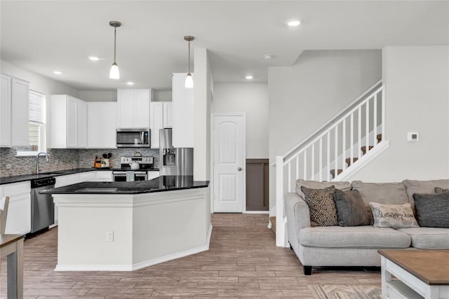 kitchen with backsplash, light wood-type flooring, pendant lighting, stainless steel appliances, and white cabinets