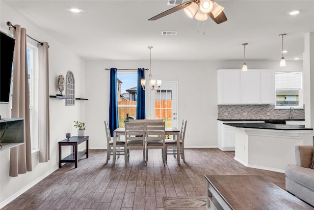 dining area with sink, hardwood / wood-style flooring, and ceiling fan with notable chandelier