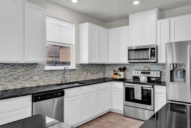 kitchen with white cabinets, decorative backsplash, stainless steel appliances, and sink