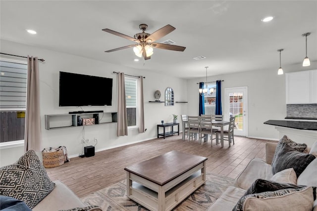 living room with ceiling fan with notable chandelier and hardwood / wood-style flooring