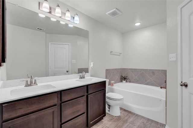 bathroom with toilet, vanity, wood-type flooring, and a tub to relax in