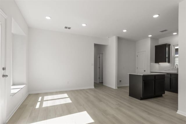 168 Bosque Dr, San Marcos, TX 78666 - kitchen featuring light wood-style flooring, a kitchen island, dark cabinetry, light countertops, and recessed lighting