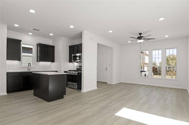 168 Bosque Dr, San Marcos, TX 78666 - kitchen featuring stainless steel appliances, dark cabinetry, a center island, ceiling fan, and a sink