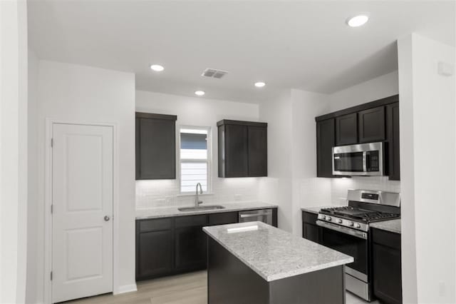 168 Bosque Dr, San Marcos, TX 78666 - kitchen featuring stainless steel appliances, a sink, backsplash, a kitchen island, and light stone counters