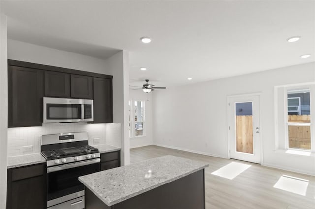 168 Bosque Dr, San Marcos, TX 78666 - kitchen featuring appliances with stainless steel finishes, a center island, decorative backsplash, light wood finished floors, and a ceiling fan