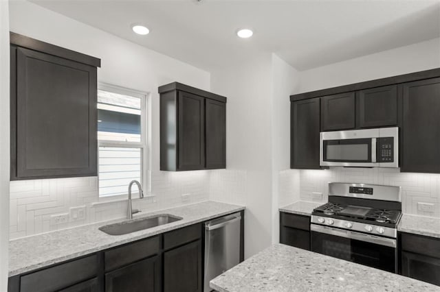 168 Bosque Dr, San Marcos, TX 78666 - kitchen featuring appliances with stainless steel finishes, a sink, light stone countertops, and tasteful backsplash