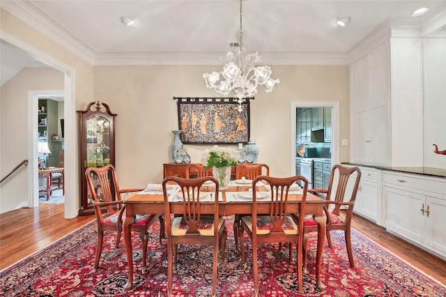 dining space featuring light hardwood / wood-style floors, crown molding, and an inviting chandelier