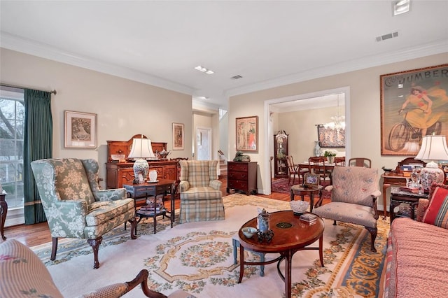 living room with ornamental molding, a chandelier, and light hardwood / wood-style flooring