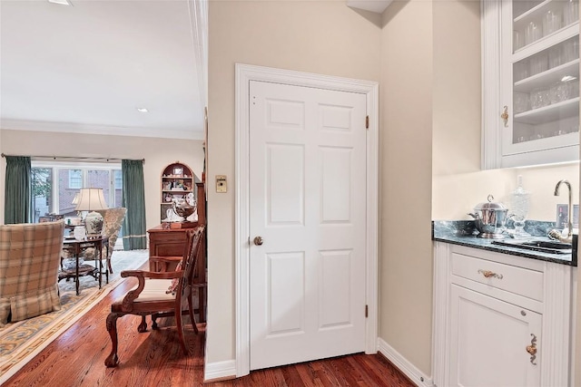 bar featuring white cabinetry, ornamental molding, sink, and dark hardwood / wood-style floors