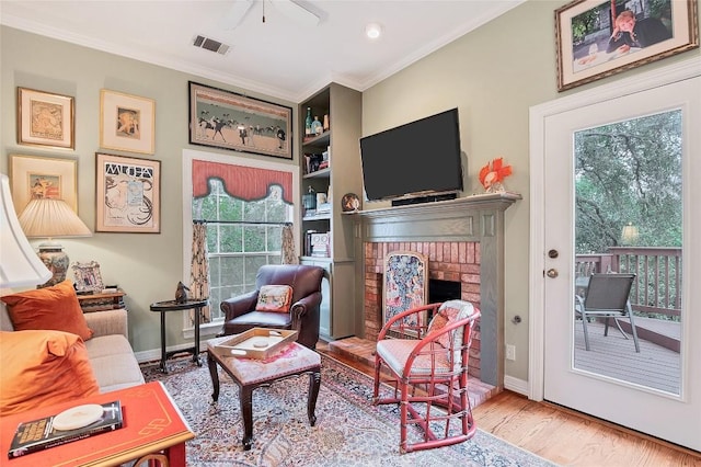 living room featuring a brick fireplace, crown molding, and hardwood / wood-style floors