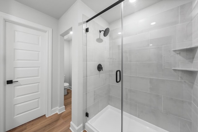 bathroom with toilet, walk in shower, and wood-type flooring