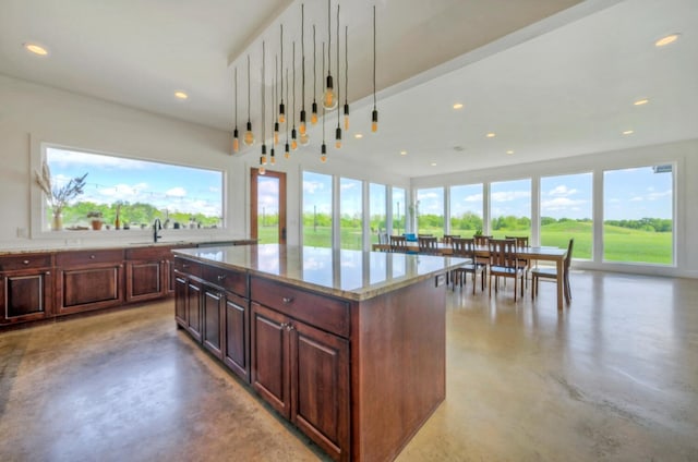 kitchen with hanging light fixtures, a center island, sink, and light stone counters