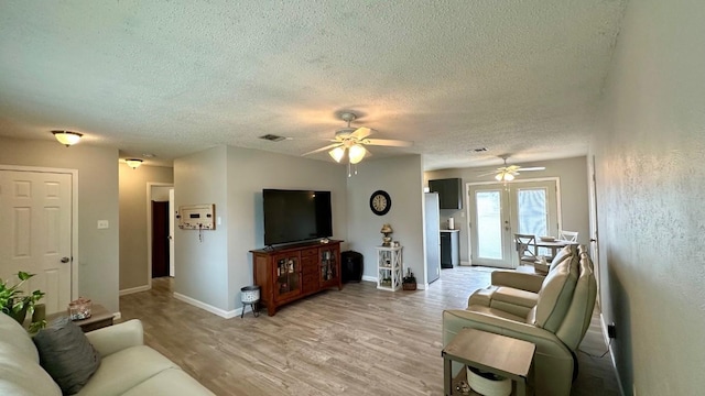 living room with light wood-type flooring, a textured ceiling, and ceiling fan