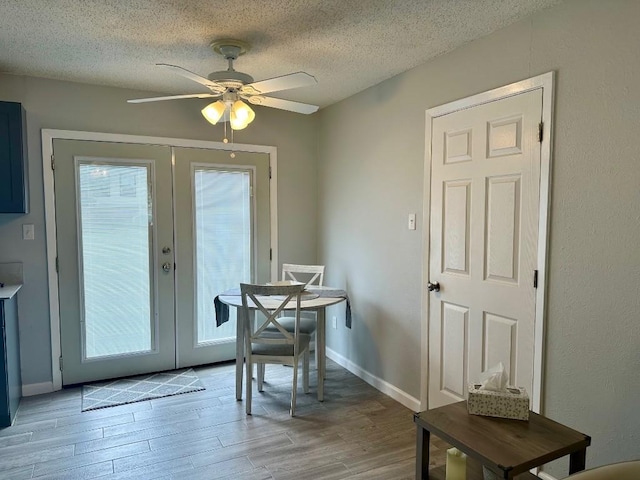 dining area with light wood-type flooring, french doors, a textured ceiling, and ceiling fan