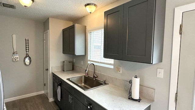 kitchen featuring decorative light fixtures, sink, a textured ceiling, and dark wood-type flooring