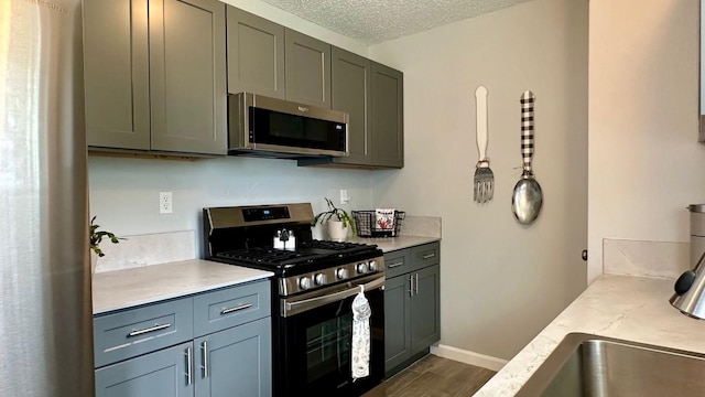 kitchen featuring decorative light fixtures, light stone counters, a textured ceiling, dark wood-type flooring, and appliances with stainless steel finishes