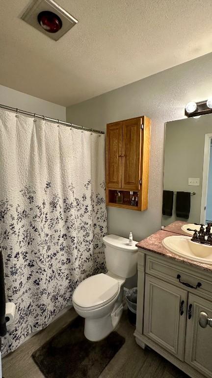 bathroom with a textured ceiling, toilet, vanity, and wood-type flooring