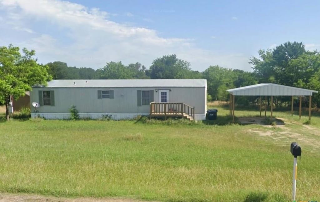 manufactured / mobile home with a front lawn and a carport