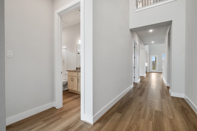 corridor with baseboards and light wood-style flooring