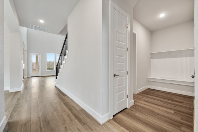 hall featuring baseboards, stairs, wood finished floors, and visible vents