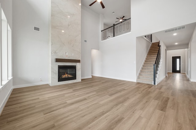 unfurnished living room with a ceiling fan, a high ceiling, visible vents, and stairway