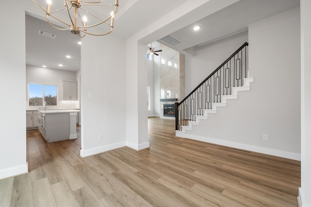 interior space featuring visible vents, light wood-style floors, and ceiling fan with notable chandelier