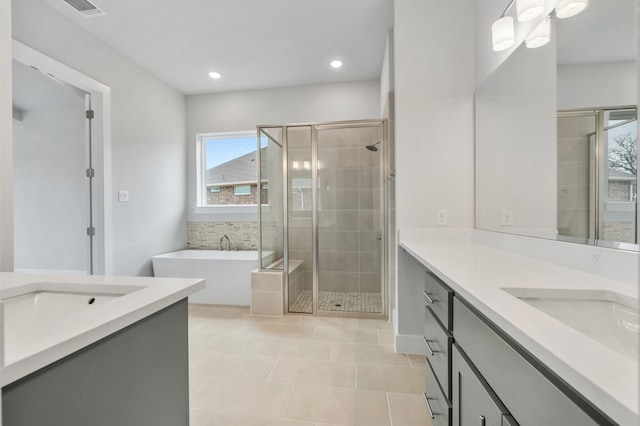 full bath with a tub, tile patterned flooring, a stall shower, and two vanities
