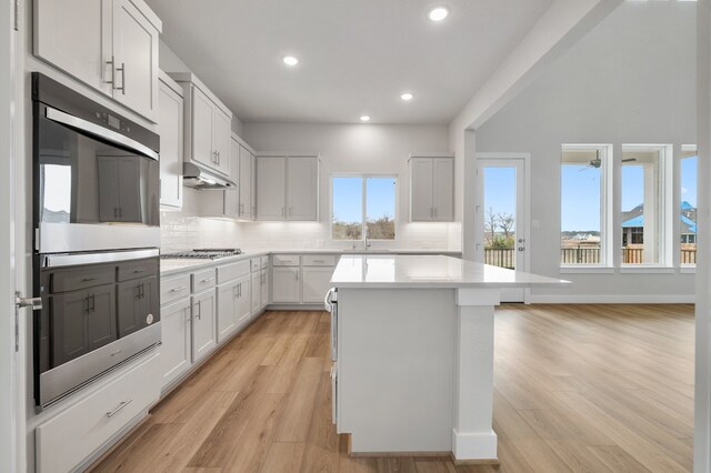 kitchen featuring a kitchen island, stainless steel appliances, backsplash, and light countertops