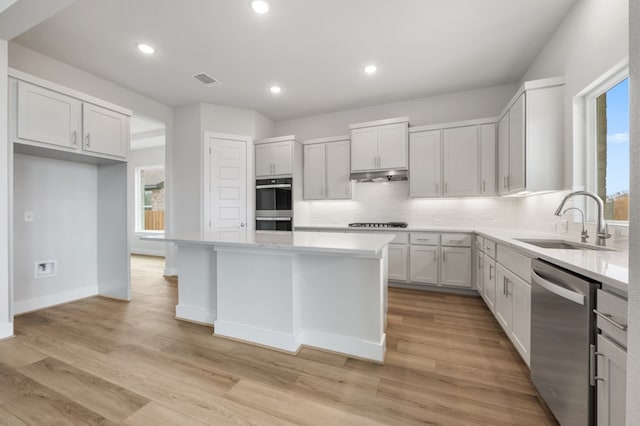 kitchen with visible vents, under cabinet range hood, tasteful backsplash, a sink, and stainless steel appliances