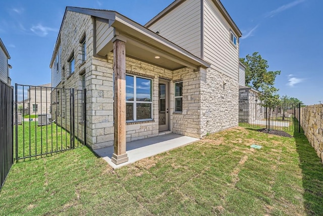 exterior space with stone siding, a yard, a patio area, and a fenced backyard