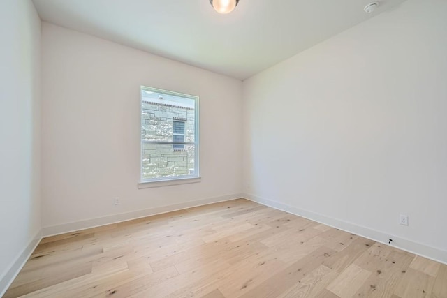 spare room featuring light wood-type flooring and baseboards