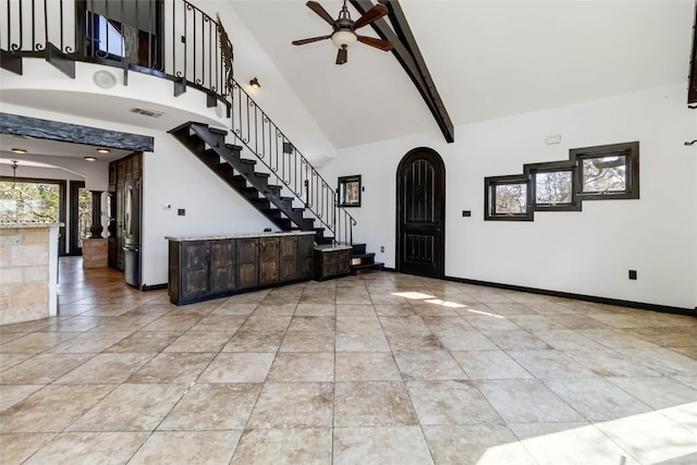 foyer featuring baseboards, high vaulted ceiling, arched walkways, ceiling fan, and stairs