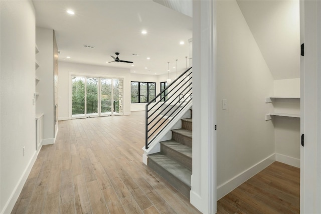 stairs with hardwood / wood-style floors and ceiling fan