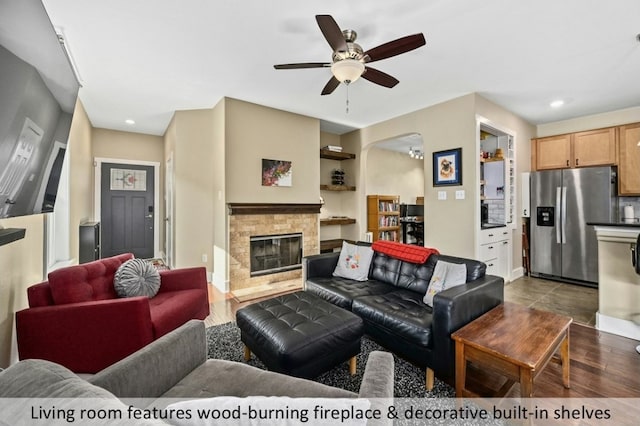 living room with hardwood / wood-style flooring, ceiling fan, and a stone fireplace