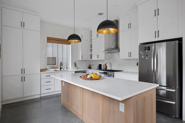 kitchen featuring white cabinetry, stainless steel appliances, a center island, light stone countertops, and sink