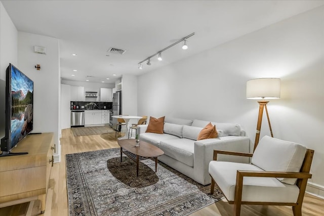 living room featuring rail lighting and light hardwood / wood-style floors