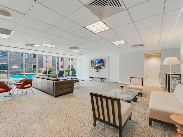 living room with a drop ceiling and light carpet