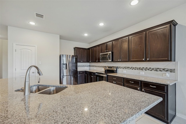 kitchen featuring appliances with stainless steel finishes, a sink, and light stone counters