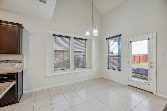 unfurnished dining area featuring visible vents, a notable chandelier, baseboards, and light tile patterned flooring