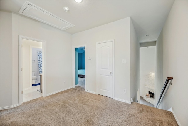 unfurnished bedroom featuring attic access, baseboards, light carpet, and ensuite bath